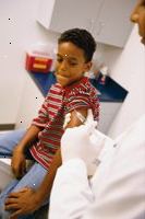 Φωτογραφία ενός νεαρού αγοριού ετοιμάζεται να πάρει έναν πυροβολισμό εμβολιασμού από τον γιατρό του